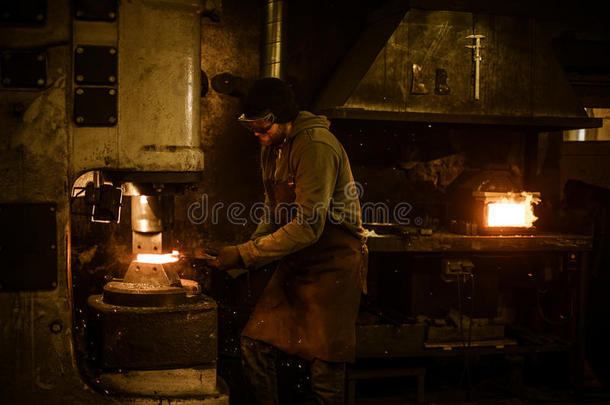 铁匠在铁匠的动力锤上锻造熔化的金属