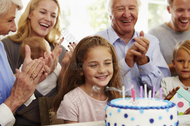 女孩在家庭聚会上吹灭生日蛋糕蜡烛