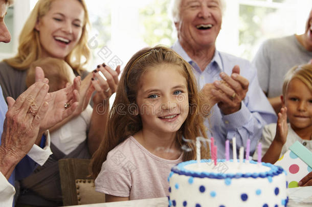 女孩在家庭聚会上吹灭生日蛋糕蜡烛