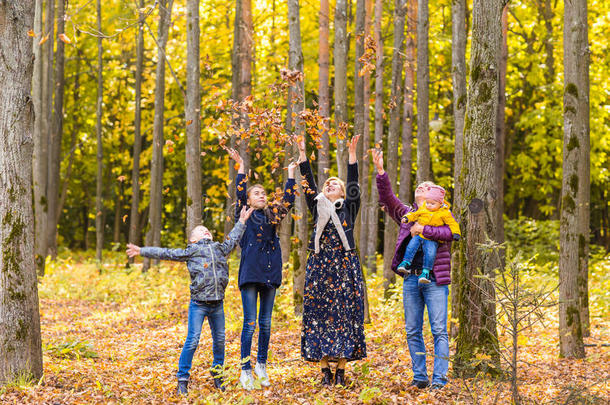 家庭，童年，季节和人的概念-快乐的家庭玩秋天的叶子在公园
