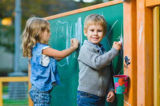 可爱的孩子们在户外用粉笔在黑板上画画