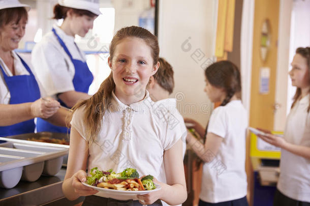 高加索女学生在学校自助餐厅拿着一盘食物