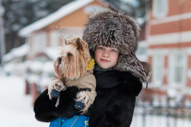 戴着毛皮帽子的女孩，冬天，霜冻的下午，和他心爱的狗约克郡猎犬散步