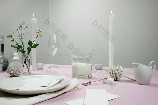 优雅的桌子设置。 桌布，牛奶，花瓶里的花，蜡烛