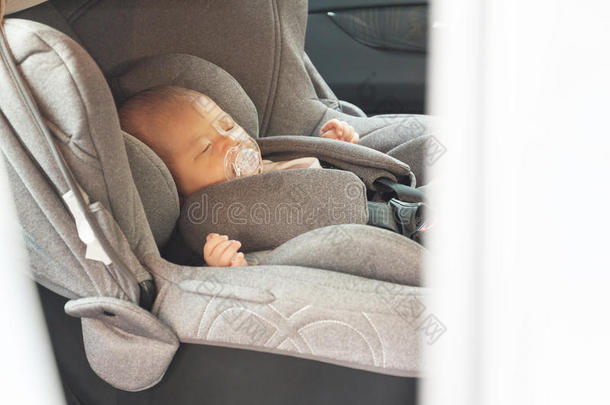 亚洲可爱的新生婴儿睡在现代汽车座椅上。