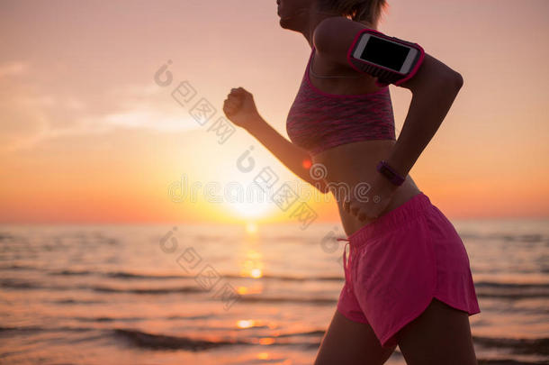 带着智能手表和<strong>音乐播放器</strong>在海滩上跑步的女孩