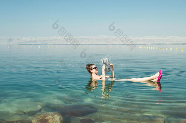 女孩看着漂浮在海面上的报纸，享受夏天的阳光和假期。 娱乐旅游，健康生活方式，免费提姆