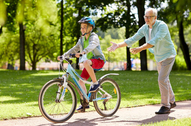 祖父和男孩在夏季公园骑自行车