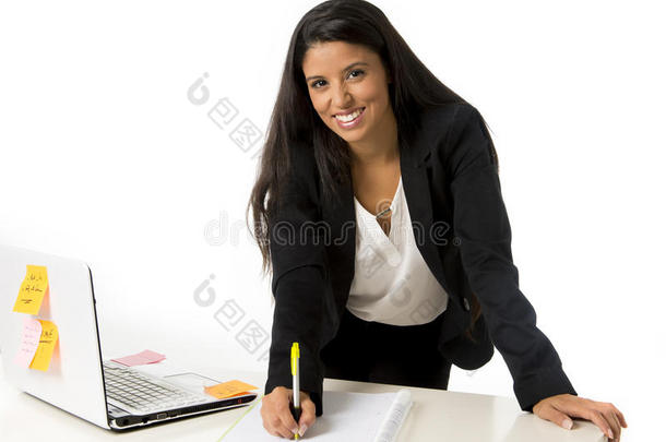 有吸引力的西班牙裔女商人或秘书站在办公室电脑桌上做笔记