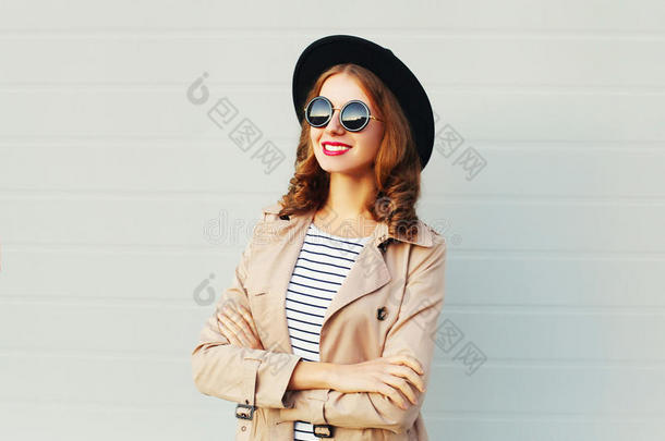时尚肖像相当快乐，微笑的女人交叉<strong>双</strong>臂，戴着黑色帽子<strong>太阳</strong>镜，戴在灰色上