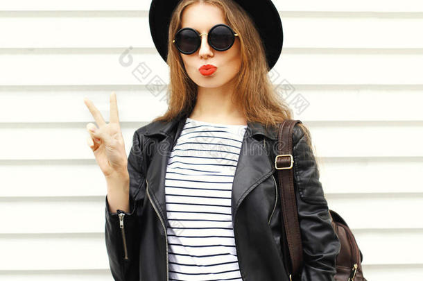 时尚的年轻女人带着黑色摇滚风格的背包超过白色