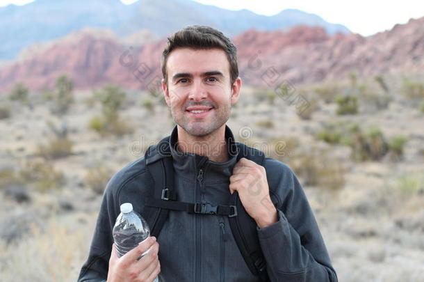 冒险，旅行，旅游，徒步旅行和人的概念-男人拿着水瓶和黑色背包在沙漠徒步旅行