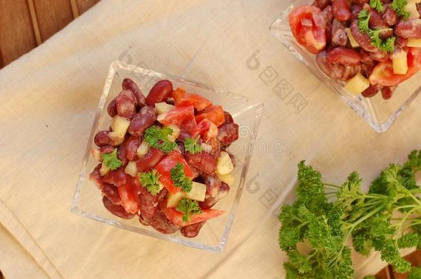 新鲜健康纯素沙拉，红豆，番茄，胡椒，红辣椒和欧芹在玻璃碗在棕色<strong>布</strong>在木制背景