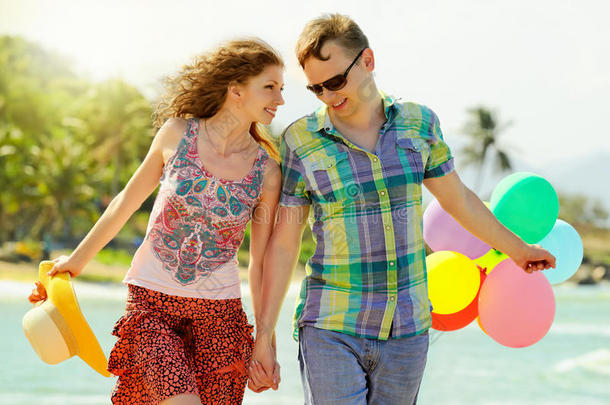 一对夫妇带着彩球在海滩上散步。