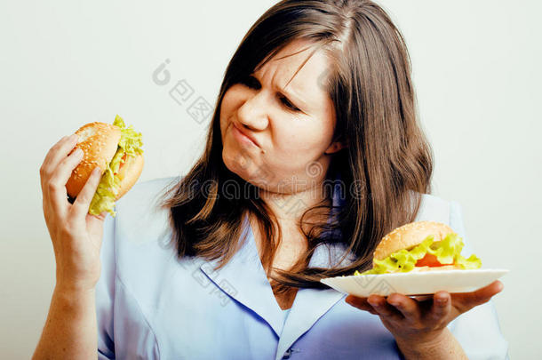 肥胖的白人妇女在汉堡包和沙拉之间有选择，吃情绪化的不健康食物，生活方式的人的概念