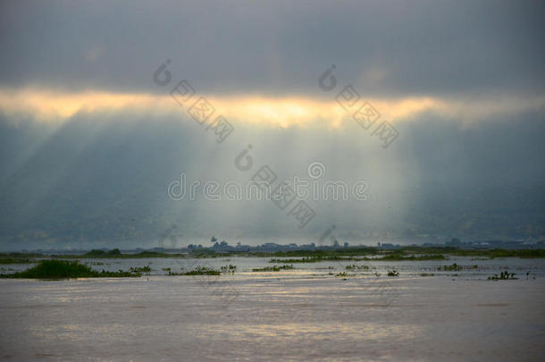 雾蒙蒙的早晨天气，阳光透过湖面上的云层照射