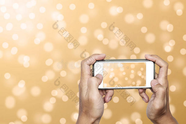 手使用智能手机拍摄离焦黄金波克灯背景的照片