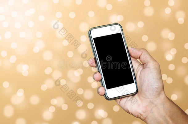 手使用智能手机拍摄离焦黄金波克灯背景的照片