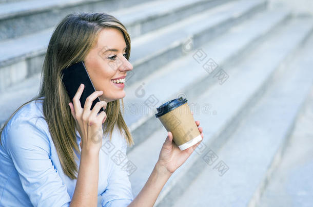 一位女商人通过手机查看电子邮件，并拿着<strong>咖啡</strong>杯面对城市<strong>场景</strong>