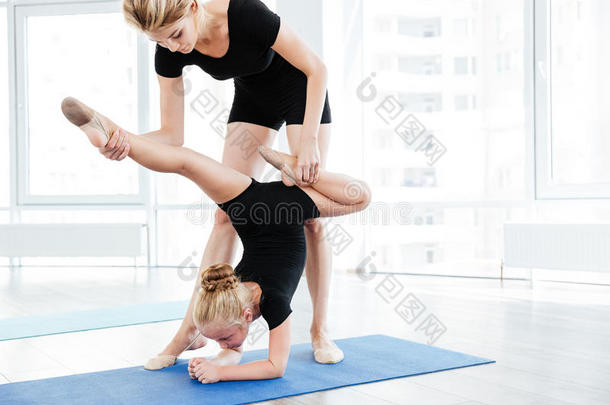 女舞蹈老师和小体操女孩一起做伸展运动