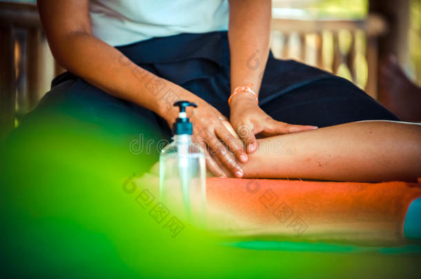 在热带花园里用手在腿上关闭油按摩水疗中心，以获得健康和健康的背景