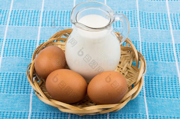桌布上柳条篮子里的棕色鸡蛋和牛奶罐