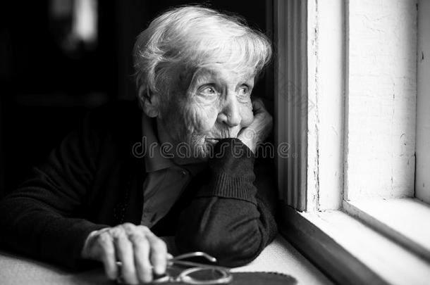 一位老妇人悲伤地望着窗外