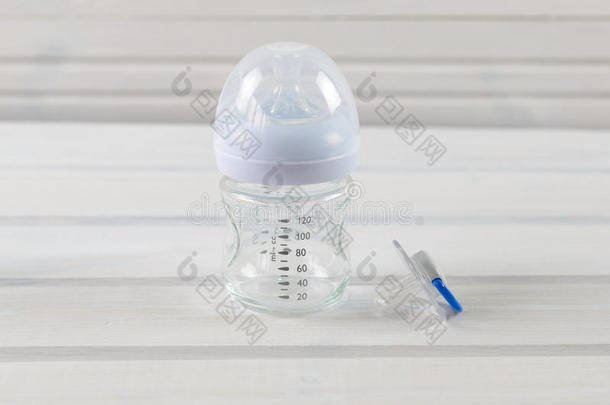 玻璃婴儿瓶和婴儿奶嘴白色木制背景
