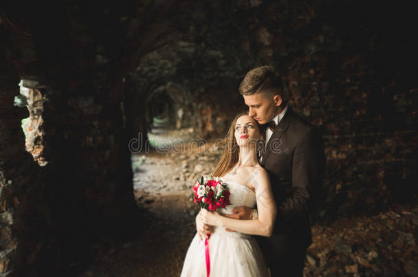 美丽的童话新婚夫妇拥抱在古老的中世纪城堡附近