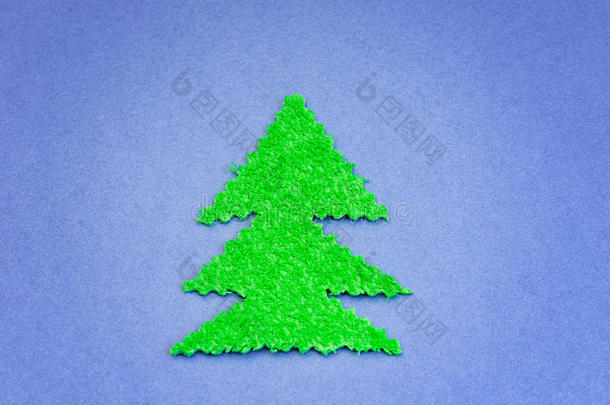绿色圣诞树从<strong>蓝色纸</strong>张表面的毛绒材料中剪下
