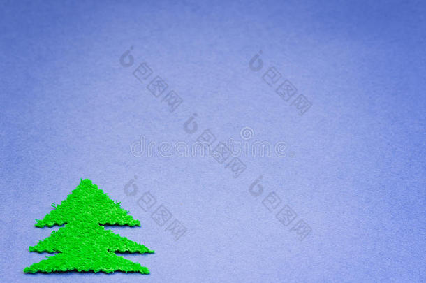绿色圣诞树从<strong>蓝色纸</strong>张表面的毛绒材料中剪下