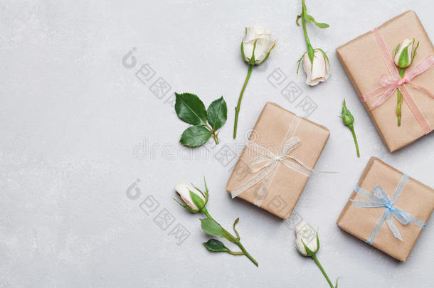 礼物或礼物盒包装在牛皮纸和玫瑰花灰色桌子上从上面。 平躺造型。 复制文本空间。
