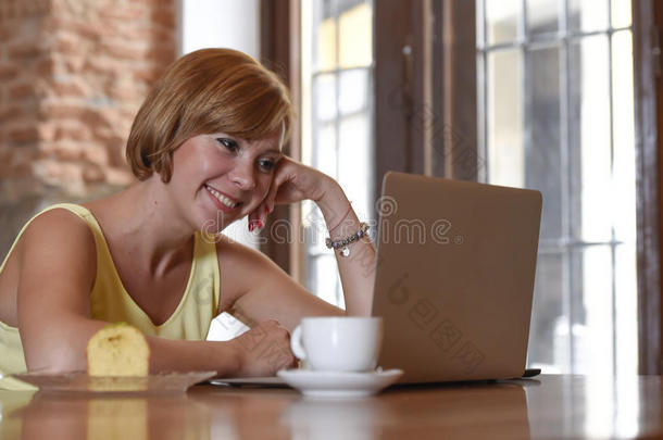 美丽的成功女人在咖啡店工作，带着笔记本电脑享受咖啡杯