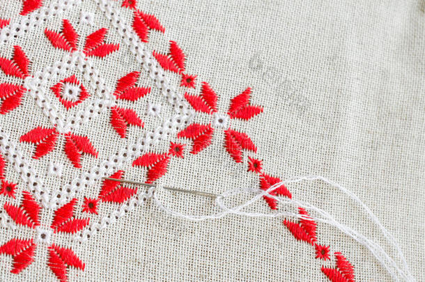 用红色和白色棉线在亚麻上刺绣碎片。 宏观刺绣纹理平针。