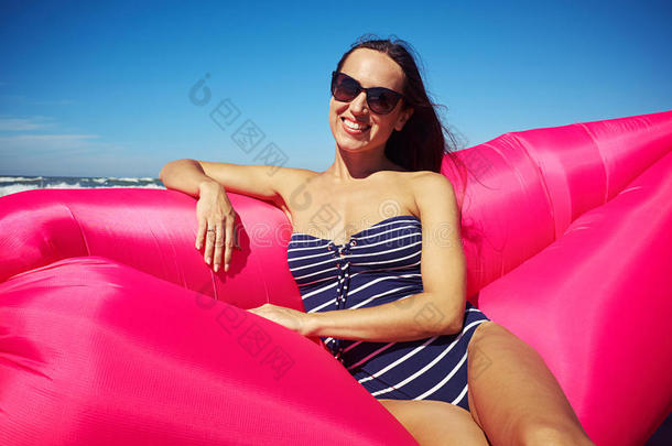 一个漂亮的晒黑的女人在一艘粉红色的<strong>充气船</strong>上摆姿势