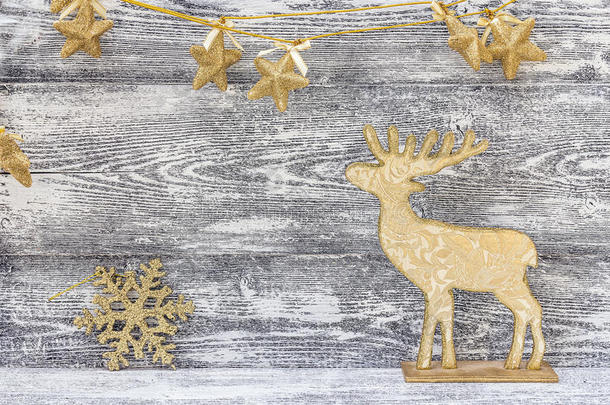 背景与金色圣诞装饰-驯<strong>鹿</strong>，雪花和星星在灰色<strong>的</strong>木板上。
