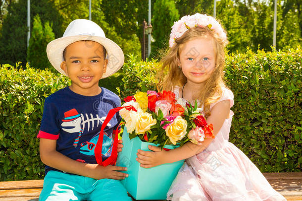 黑人非裔美国男孩在生日那天给女孩送花。 公园里可爱的小孩子。