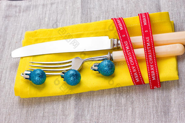 圣诞节新年背景。 把叉子，刀，勺子放在黄色餐巾上，装饰节日金丝带，蓝色球