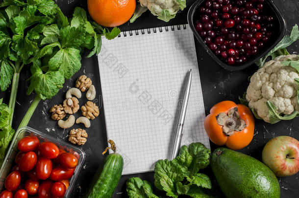 食物背景。 黑色背景上的新鲜蔬菜、水果和空白记事本。 健康饮食的概念
