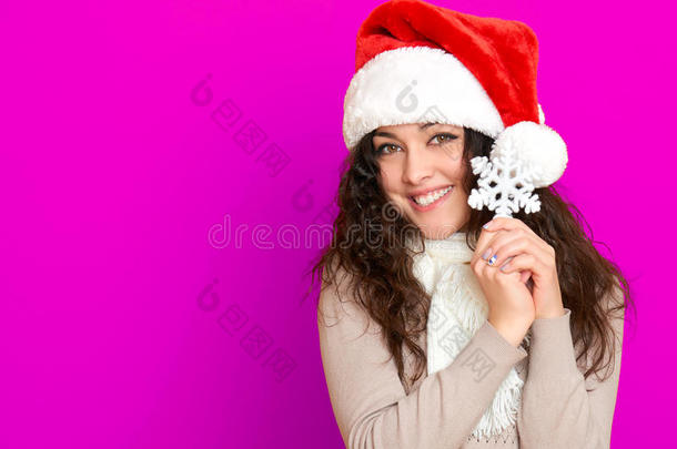 女孩在圣诞帽肖像与大雪花玩具摆在粉红色背景，圣诞节假期的概念，快乐和情感