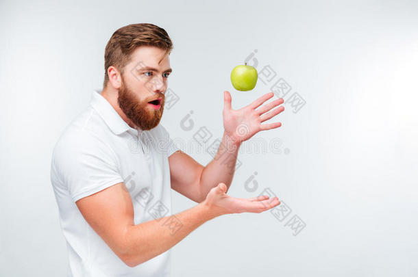 有趣的大胡子男人吐了一个绿色的苹果