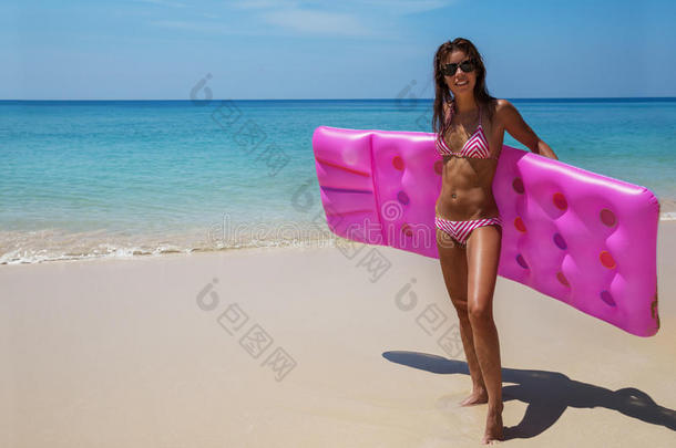 黑发女人太阳镜日光浴与空气床垫在热带海滩
