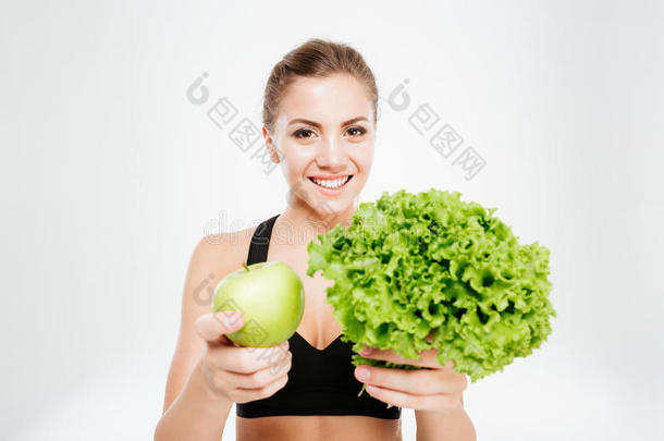兴奋微笑的运动女人<strong>展示</strong>生菜和绿色<strong>苹果</strong>