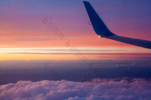 日落时分，飞机在云层上空飞行。窗外的景色