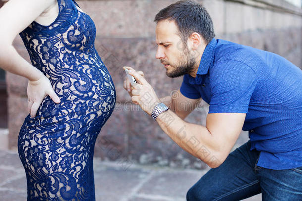 有趣的形象。 男人在电话里拍怀孕的肚子。