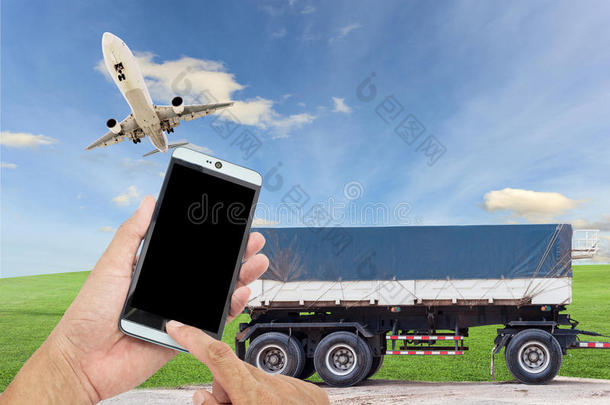 手持智能手机与飞机在天空和卡车运输蓝天背景，概念商务运输