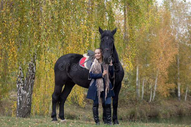 秋天在桦树下骑着黑马的女孩