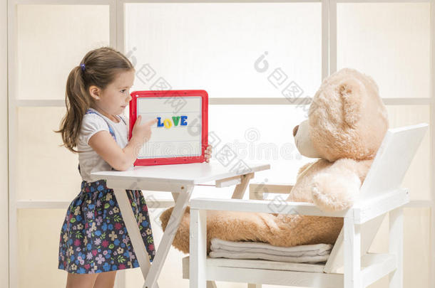 可爱的幼儿用她的玩具玩老师角色游戏