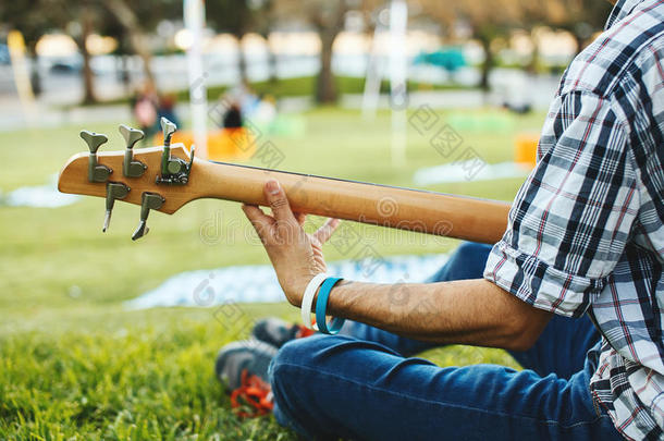 坐在草地上弹吉他的人的手
