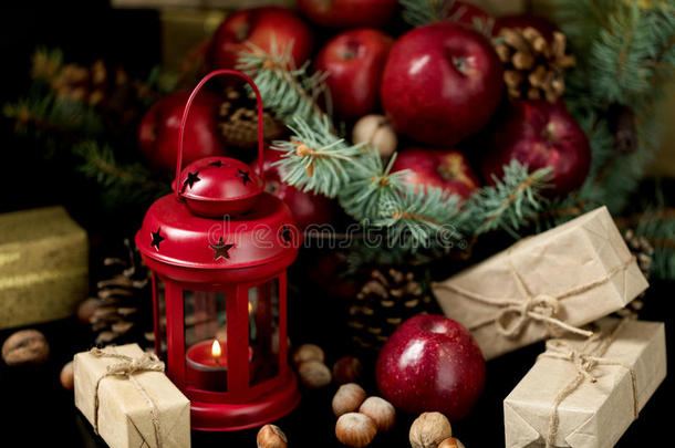 圣诞节和新年。苹果、松果和坚果放在一个有冷杉树枝的篮子里。礼物和蜡烛。